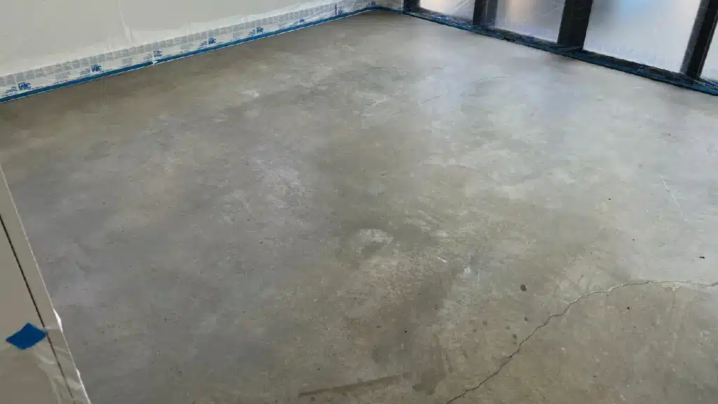 Concrete game room floor before grinding and polishing showing dull finish and surface inconsistency.