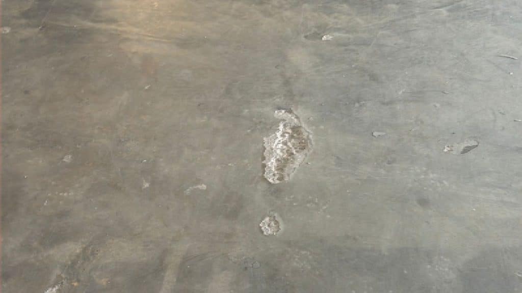 Concrete floor before polishing showing surface holes and damage after epoxy removal in Westchase Houston, TX.