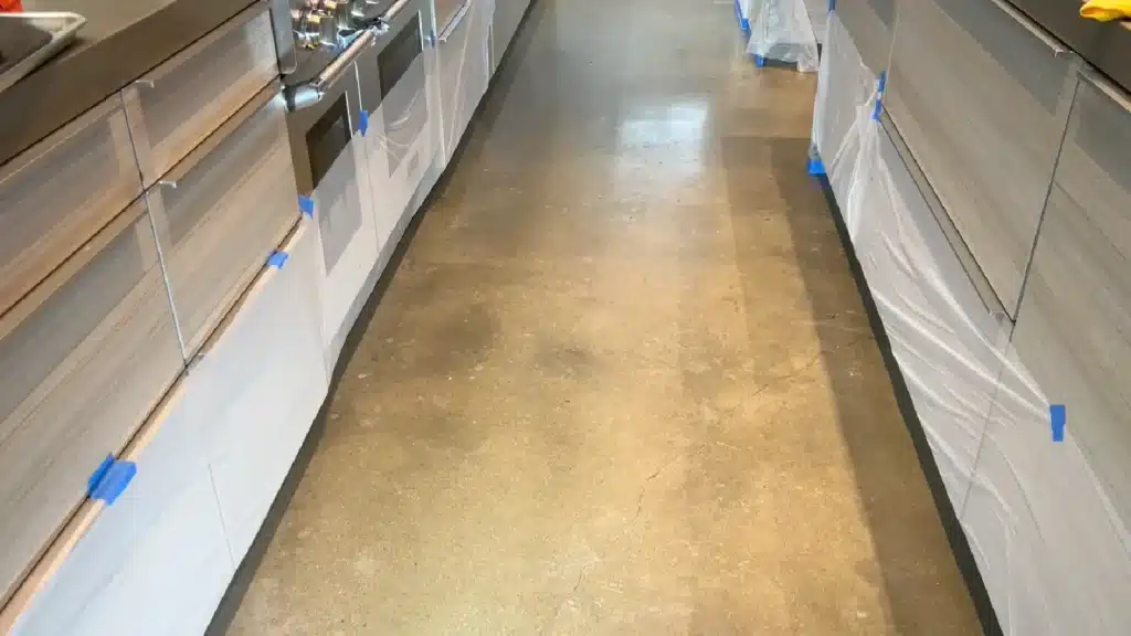 Concrete kitchen floor before grinding and polishing showing dull finish and surface variation.
