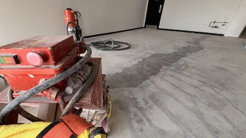 Concrete floor grinding in progress to remove thick epoxy coating prior to polishing in Westchase Houston, TX.