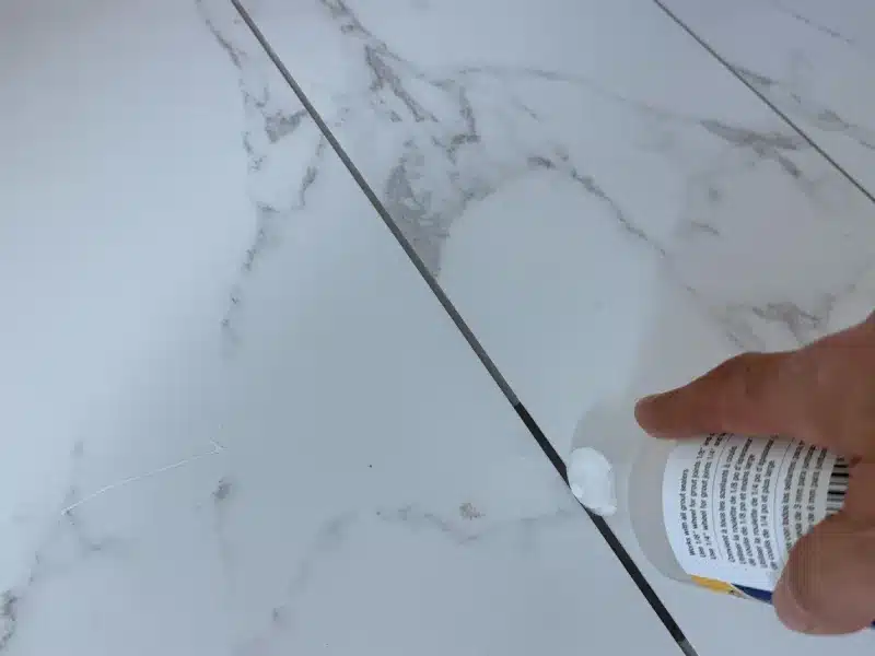 Applying grout sealer to porcelain tile floor joints to protect grout from moisture and staining