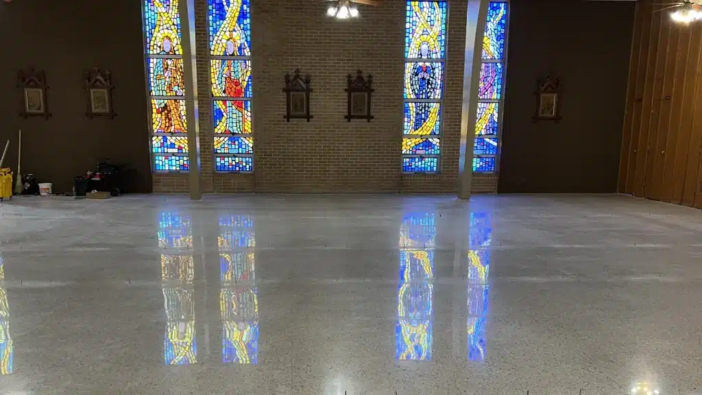 Stained glass window reflections visible on restored terrazzo floor inside Immaculate Conception Church in Goliad, TX
