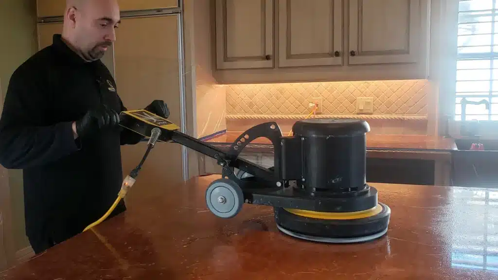 Marble kitchen countertop being honed during restoration to reduce etching and surface wear in Kemah, Texas.