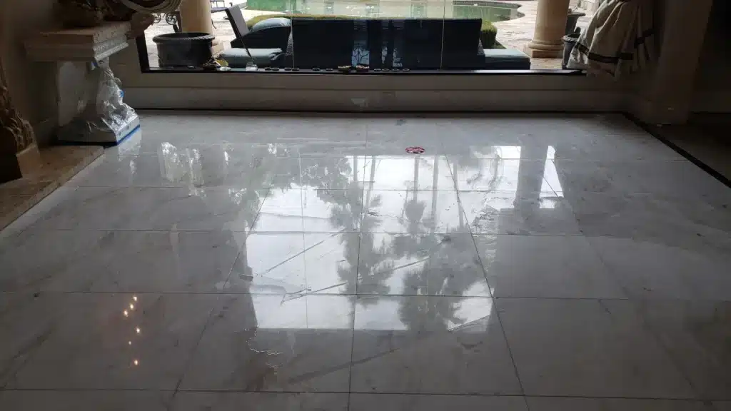 Marble living room floor before polishing showing dull surface and visible scratches from heavy foot traffic.