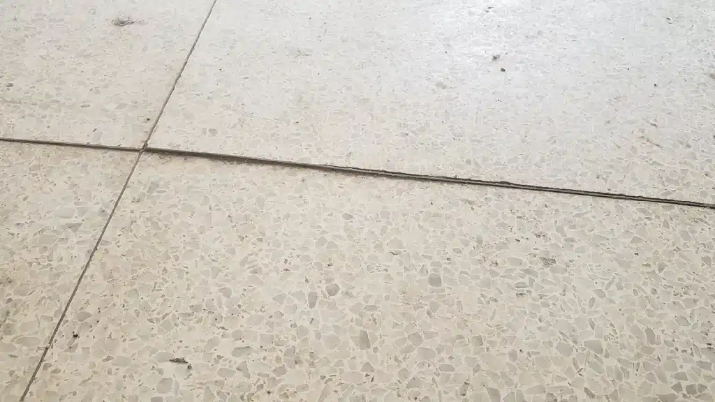 Terrazzo floor before restoration showing significant lippage and uneven panel transitions.