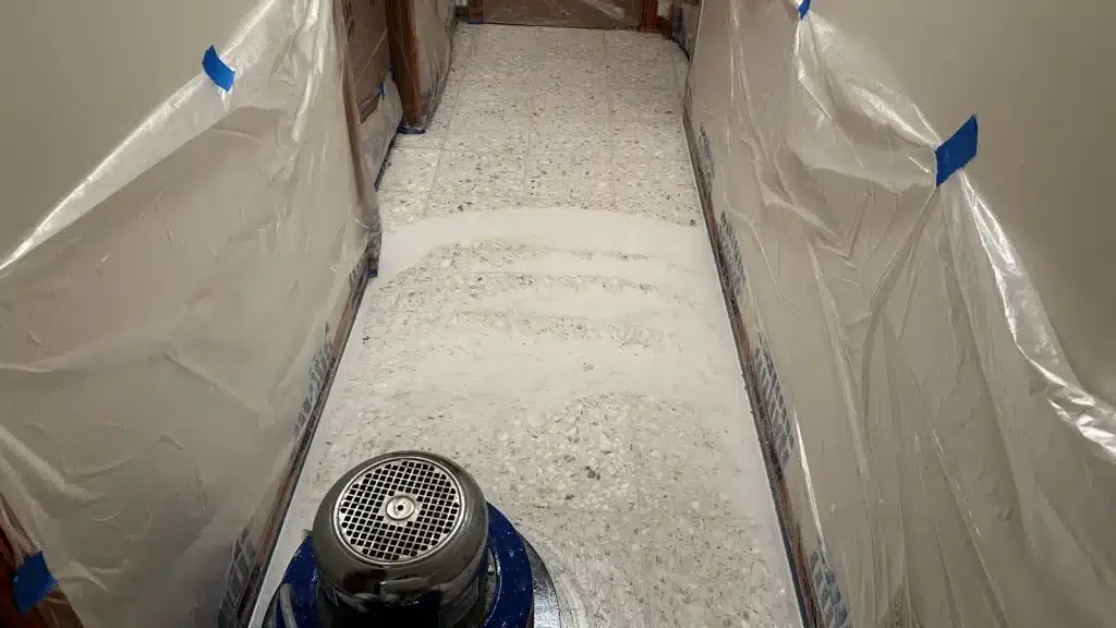 Terrazzo hallway floor during restoration process with protective wall covering and grinding in progress in Goliad, TX