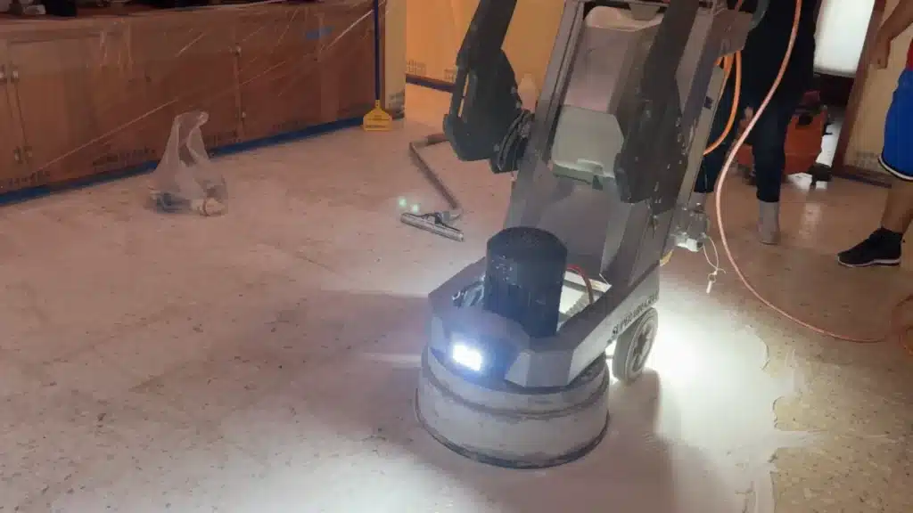 Terrazzo living room floor during restoration with professional grinding equipment in use in Goliad, TX