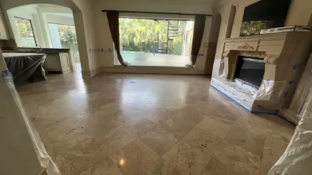 Travertine living room floor before polishing showing scratches, etching, and dull surface areas.