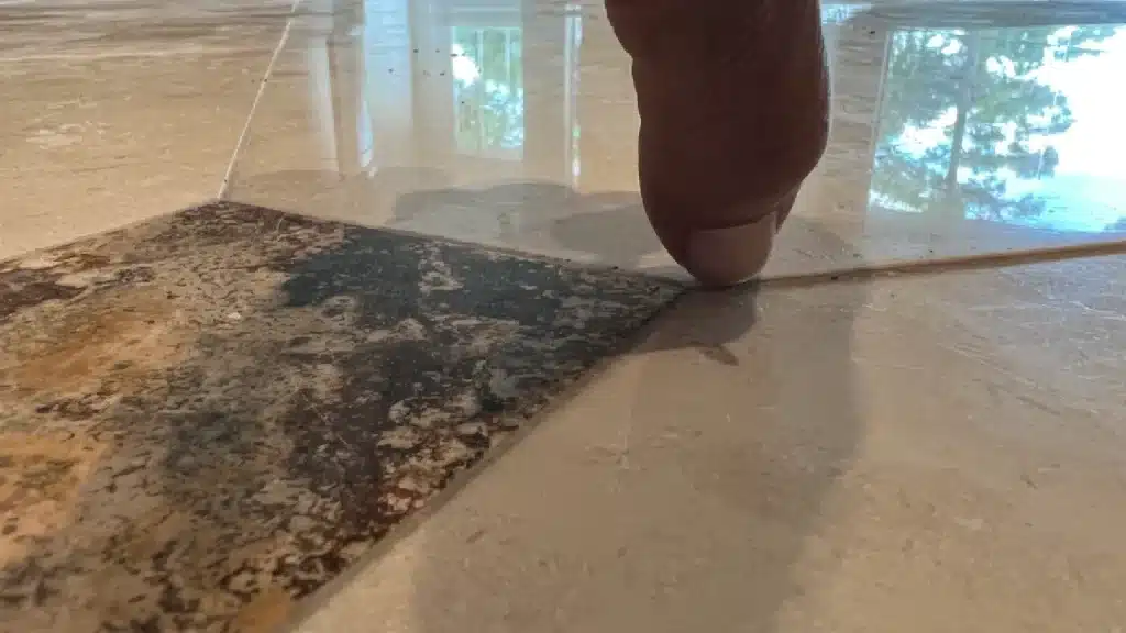 Close-up of uneven marble floor tiles showing height differences between tiles before restoration in Royal Oaks, Houston, Texas.