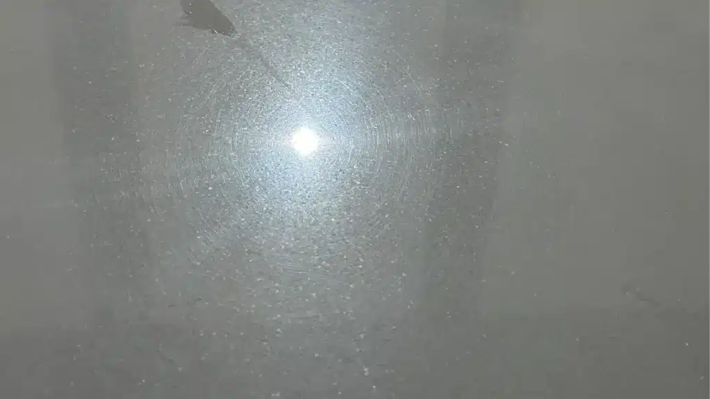 Polished White Thassos marble floor showing fine surface scratches under light reflection.